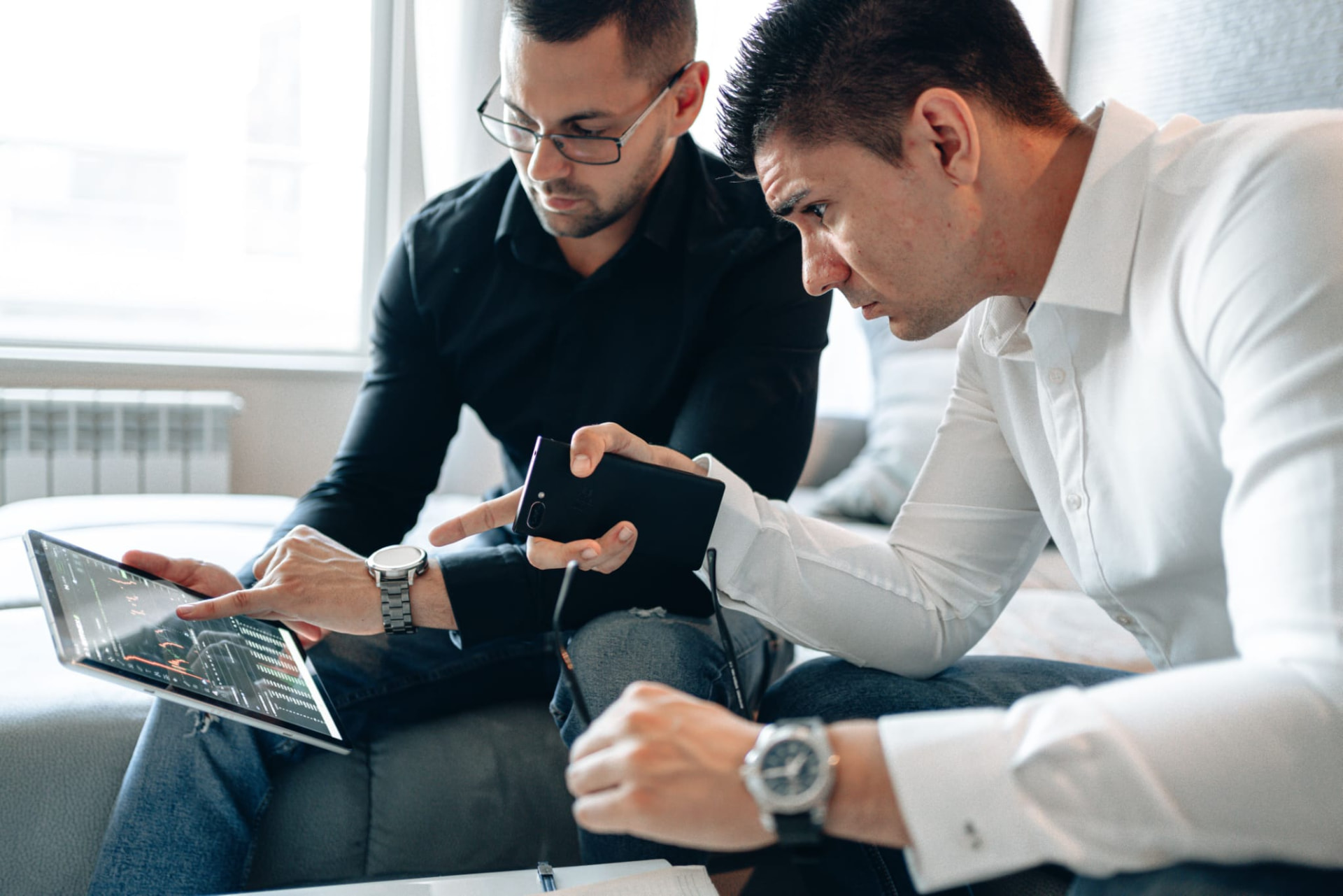 Two professionals reviewing market data and investment charts on a tablet